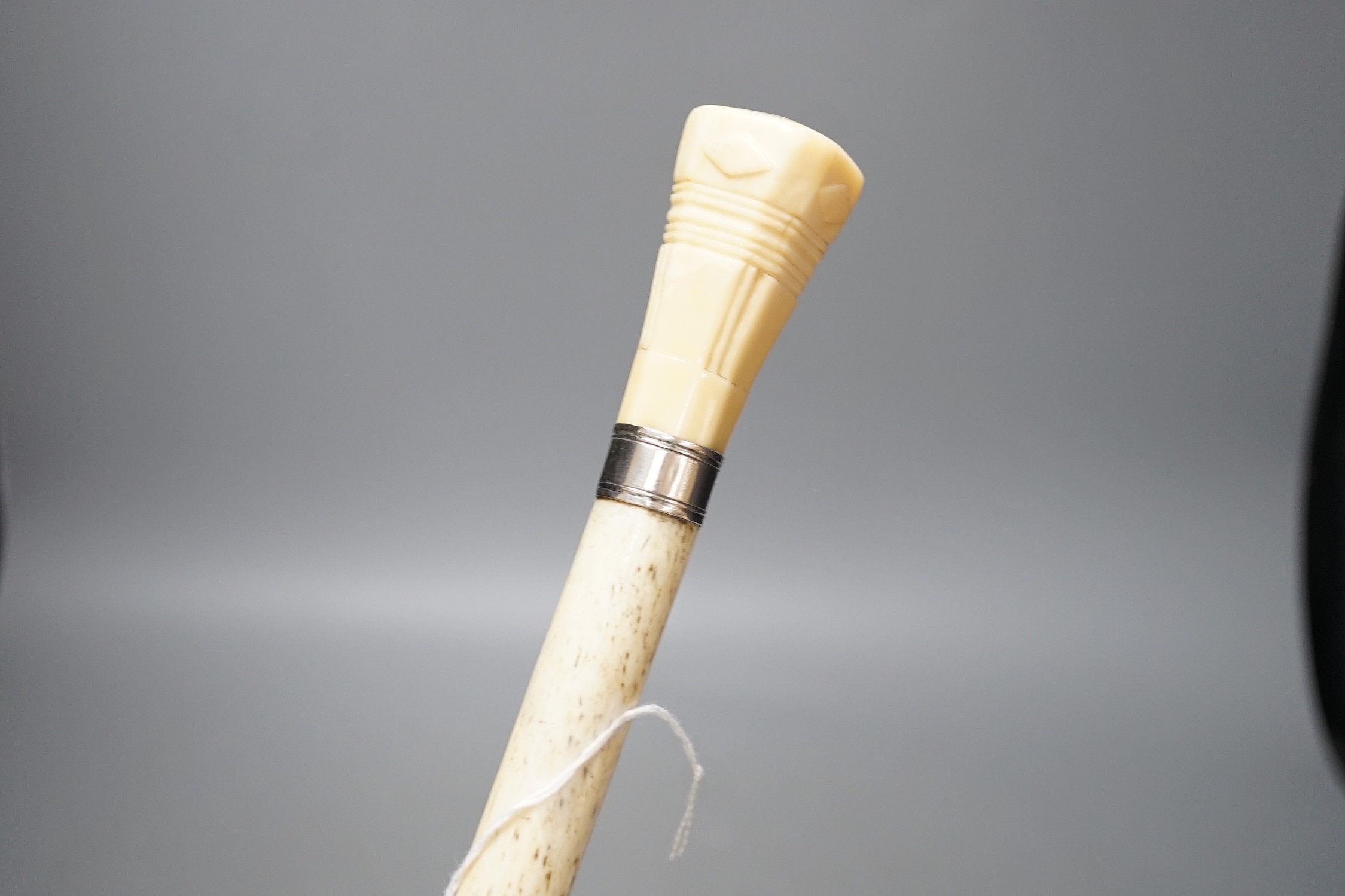 A whale bone walking stick with a whale tooth carved handle, with silver mount, 19th century